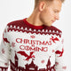 En mand kigger den ene vej og er iført en rød og hvis julesweater med mønster, juletræer og drager.