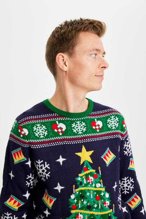 En mand kigger til siden og er iført en julesweater med mønster på.