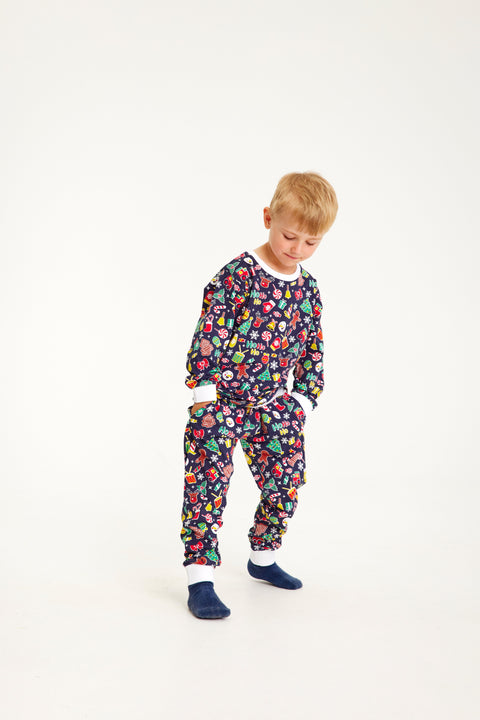 En barn er iført en blå julepyjamas med julemønster på.