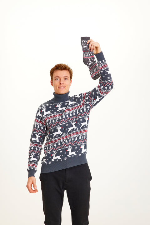 En mand holder en julesok i samme print som hans julesweater.